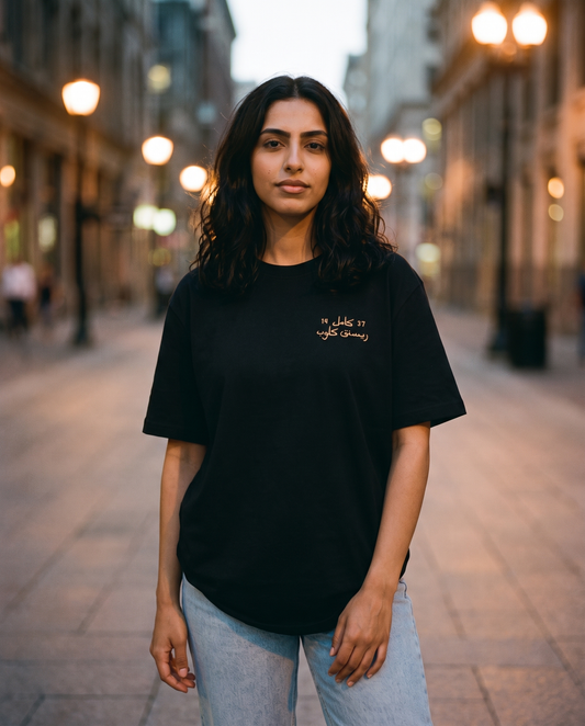 Million Street Tee gold Arabic chest print worn by female model on a lamplit street at dusk