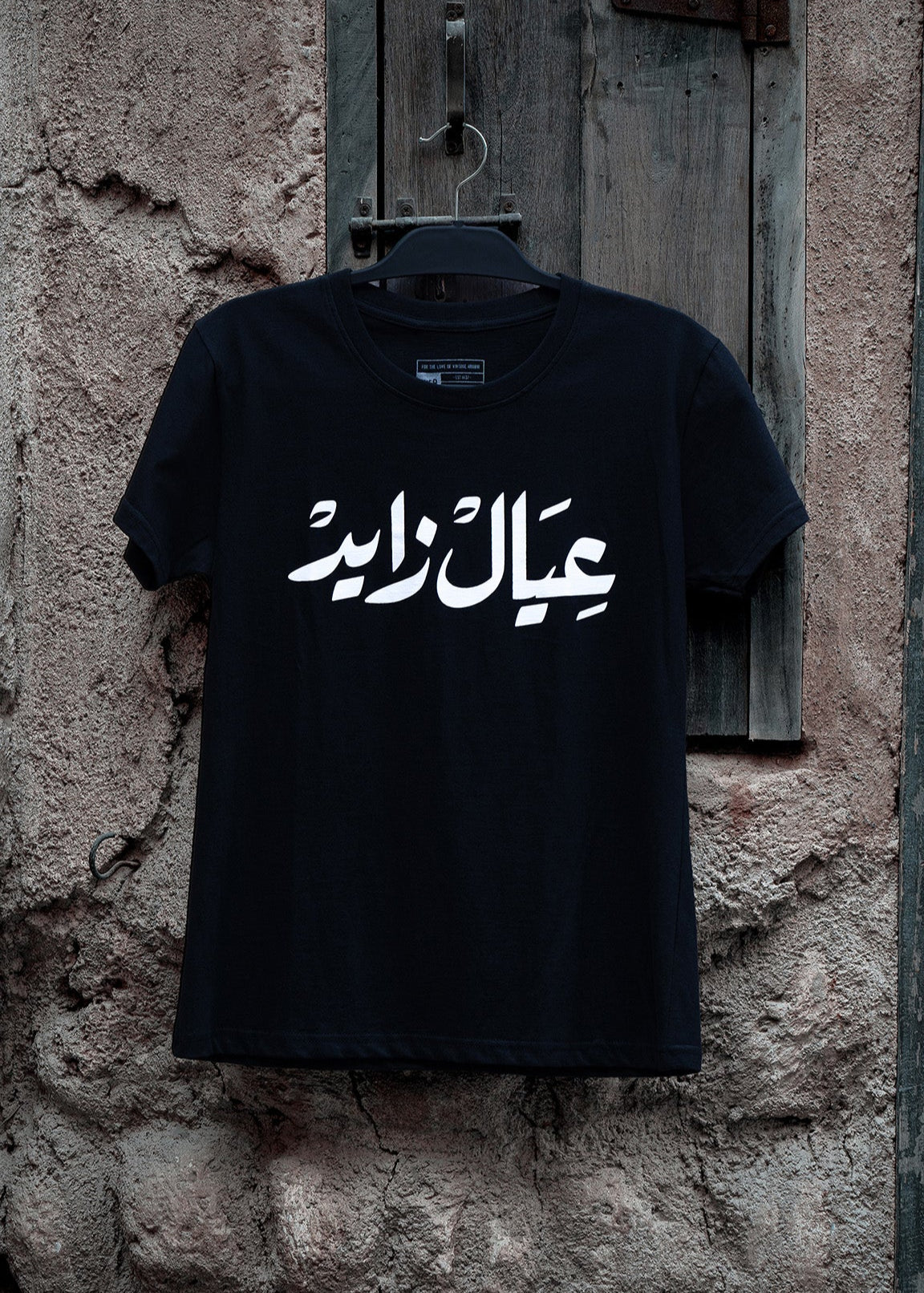 Ayal Zayed T-Shirt : black ladies T-shirt with bold Arabic calligraphy عيال زايد celebrating the UAE