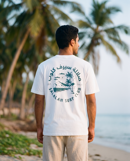 Salalah Surf Club Coconut Palms tee back print worn by male model on Salalah beach