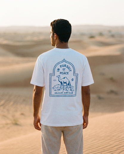 Salalah Surf Club Camel tee back print worn by male model in desert dunes at golden hour