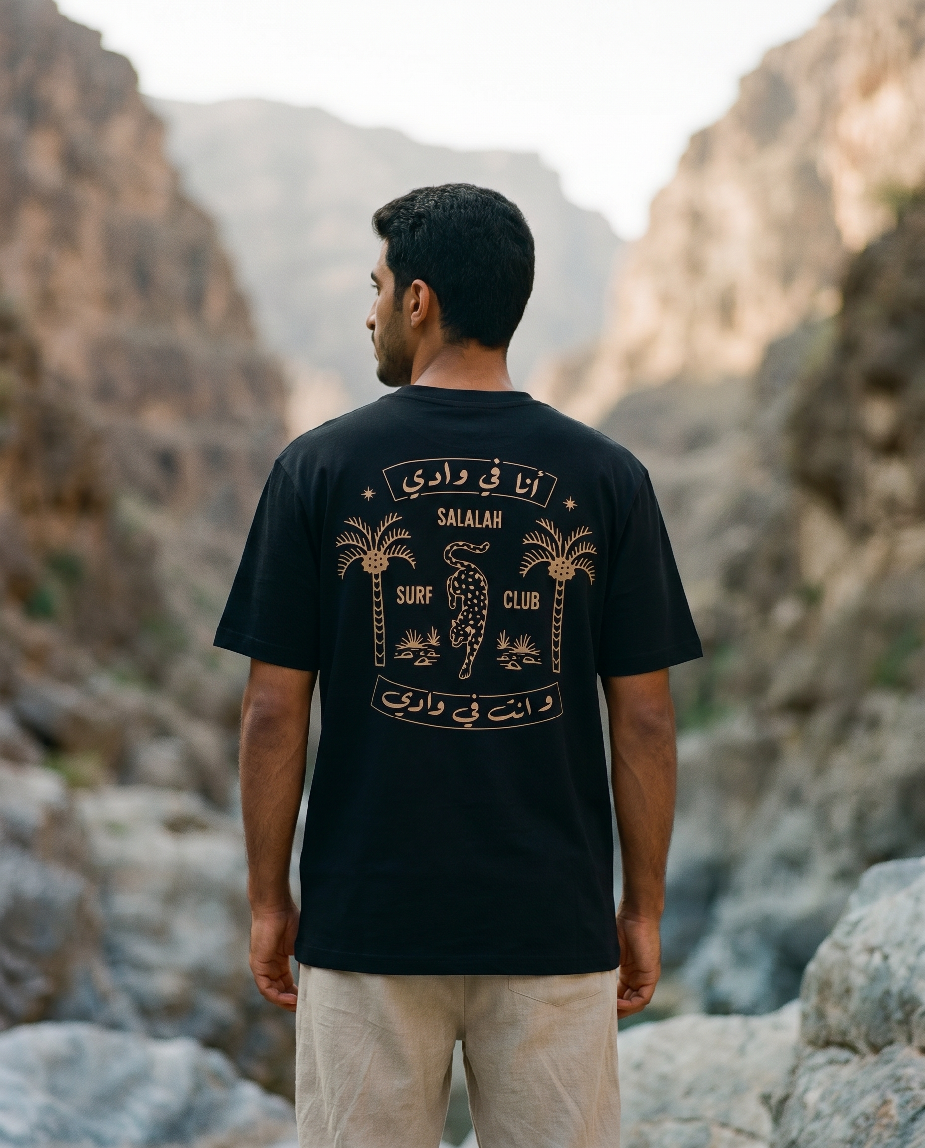 Salalah Surf Club Arabian Leopard black tee back print worn by male model in a rocky wadi
