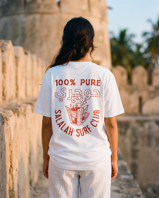 Salalah Surf Club Omani Gold tee back print, female model at Omani fort