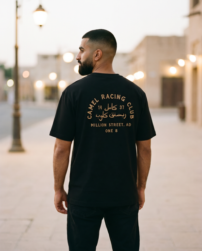 Million Street Tee Camel Racing Club gold back print worn by male model on an old Dubai street at dusk