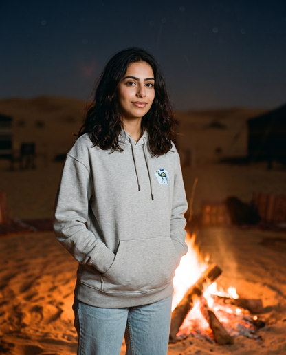 Skeleton camel hoodie in heather grey worn by female model beside a desert campfire at night