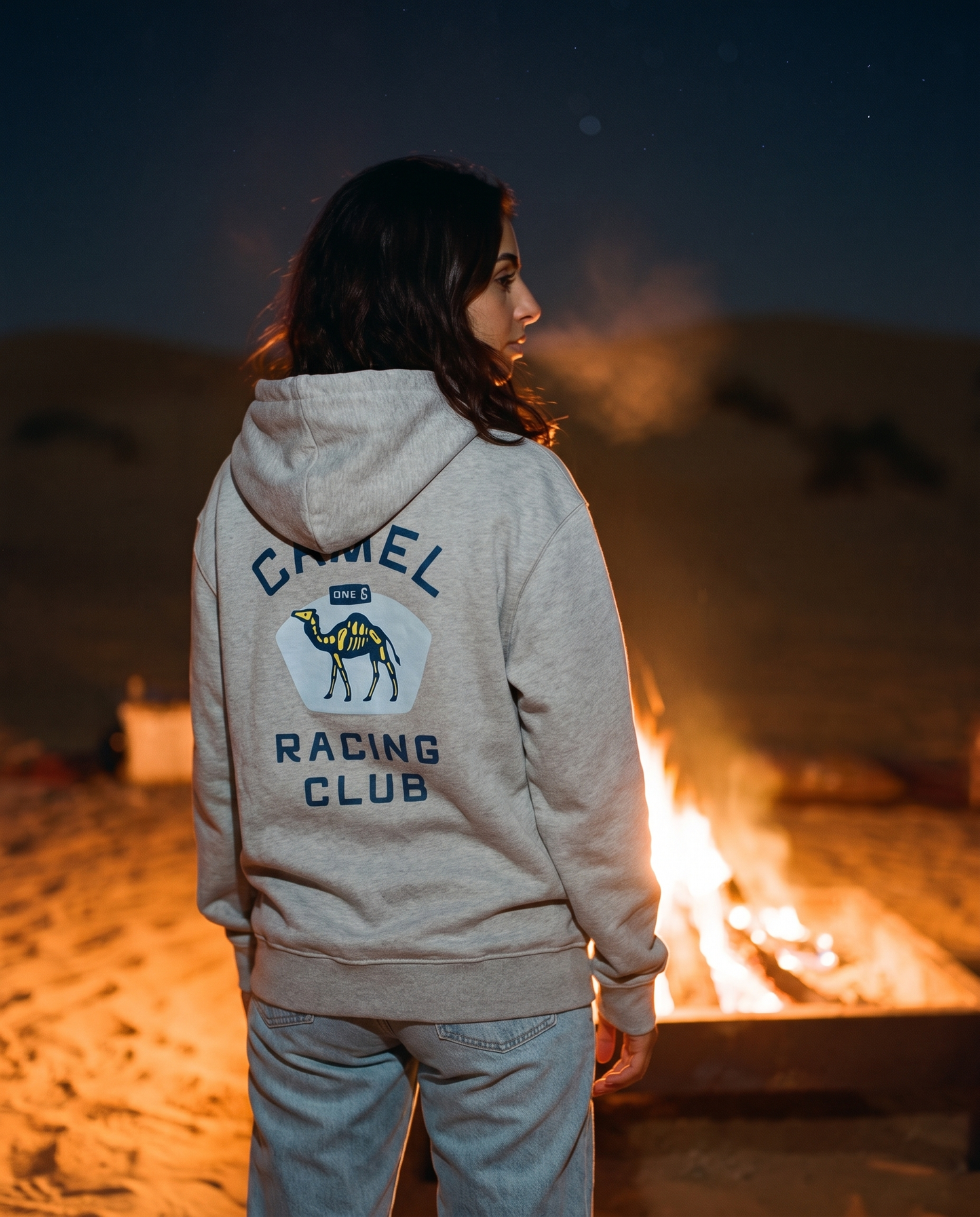 Skeleton camel hoodie Camel Racing Club back print worn by female model at a desert campfire