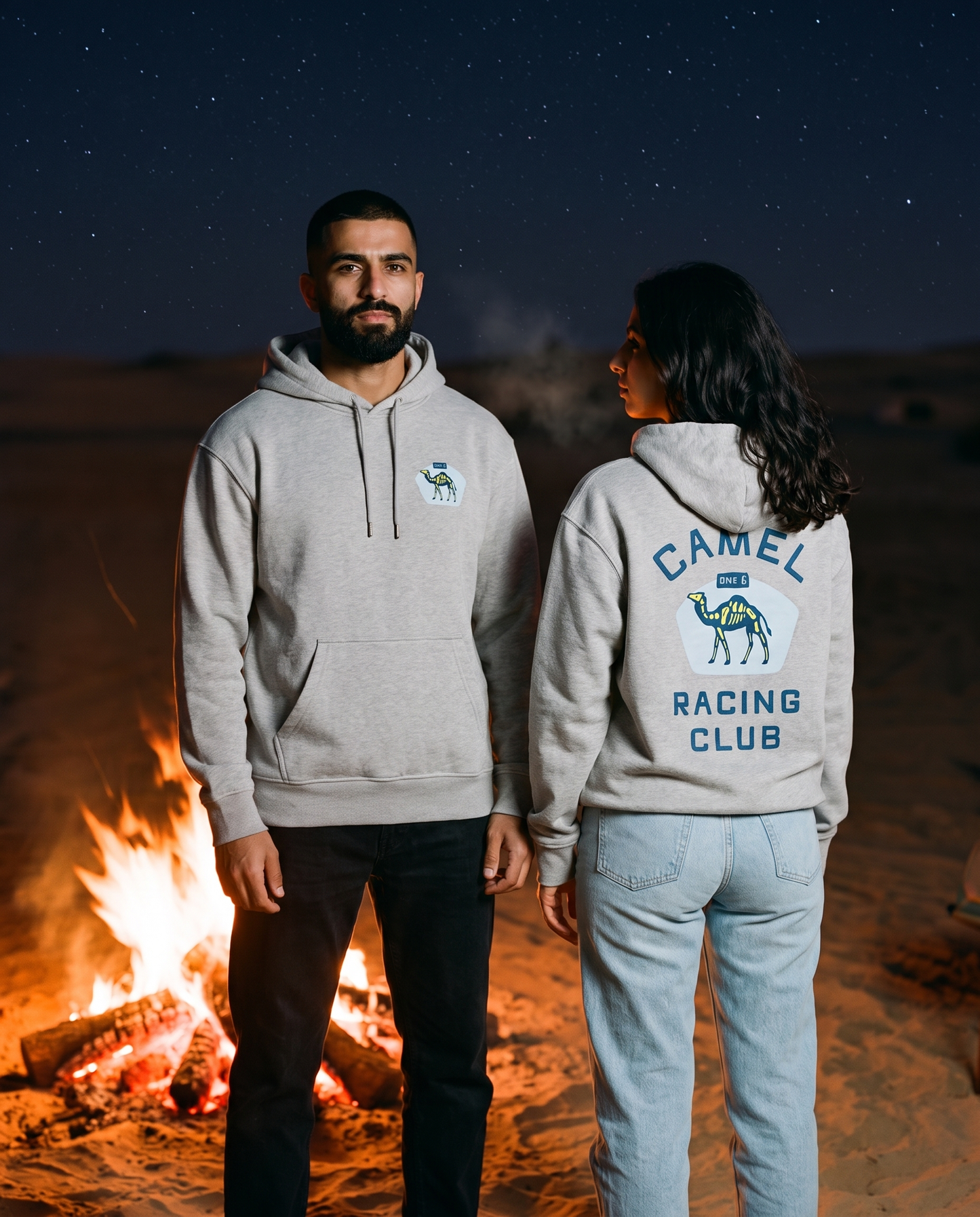 Skeleton camel hoodie in heather grey worn by male and female models at a night desert campfire, front and back view