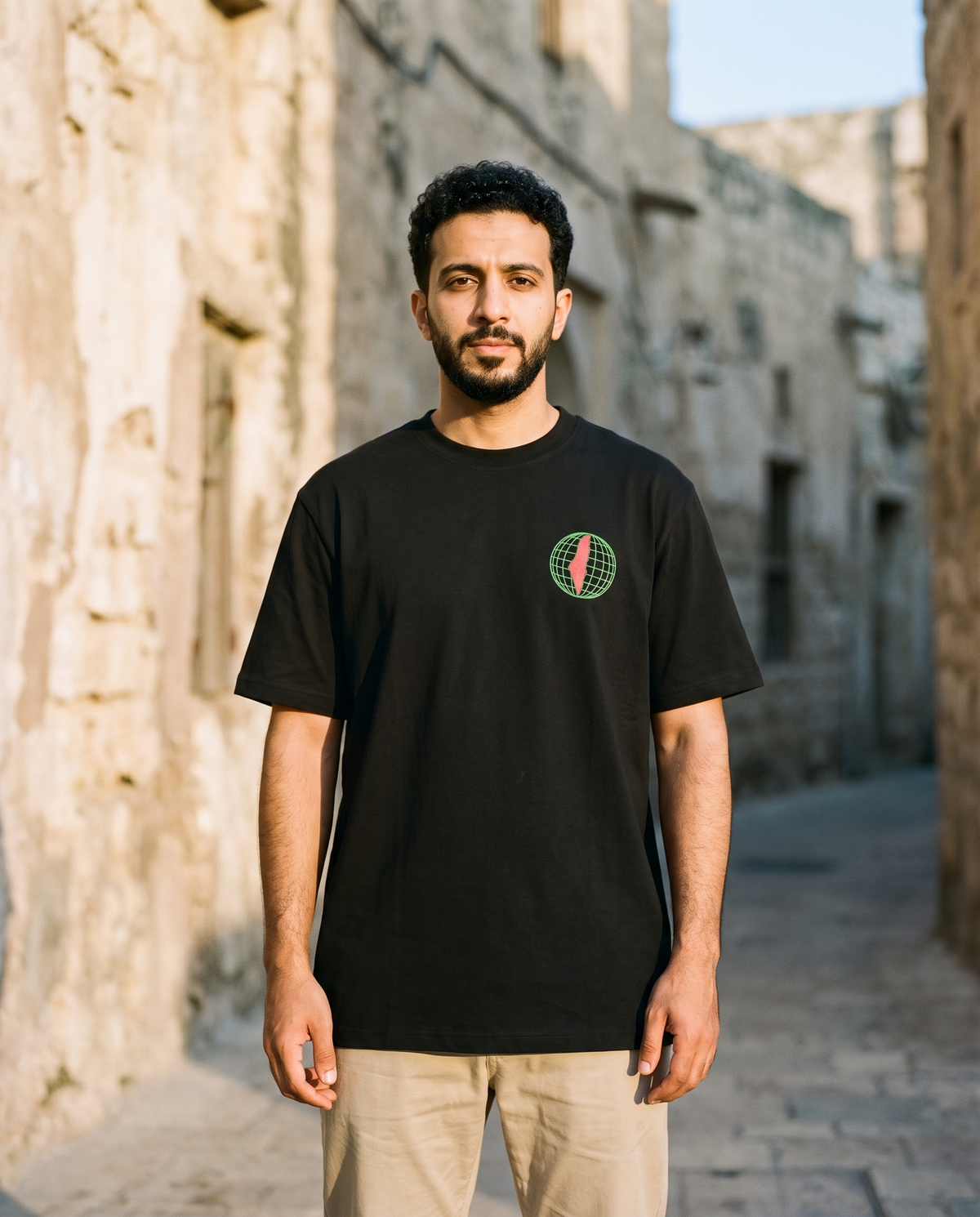 Free Palestine black tee globe chest print worn by male model in an old stone alley