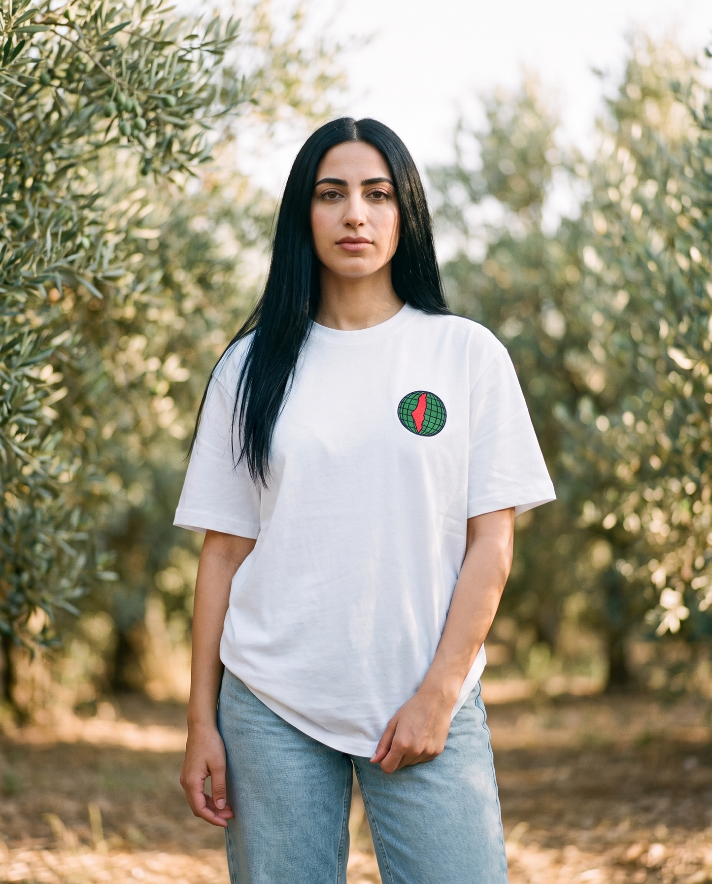 Free Palestine white tee globe chest print worn by female model in an olive grove