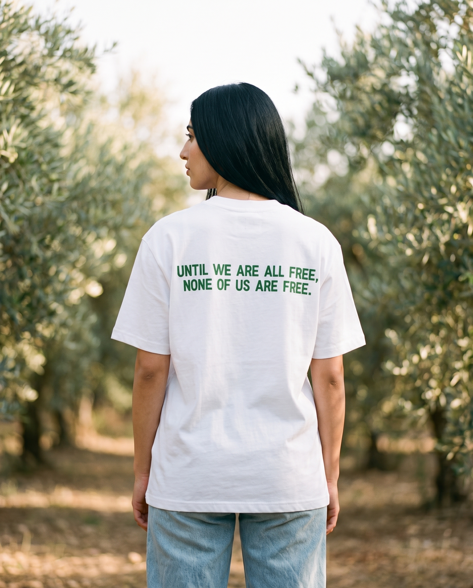 Free Palestine white tee back print worn by female model in an olive grove