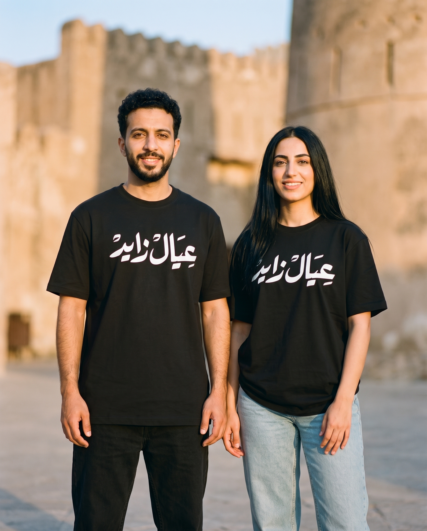 A'yal Zayed unisex tee worn by male and female models at a heritage fort