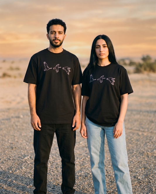 Houbara in Flight tee worn by male and female models on a desert plain at golden hour