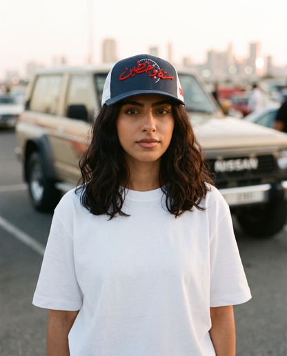 Sitta Wa Khattain curved brim trucker hat worn frontwards by female model at a classic car meet