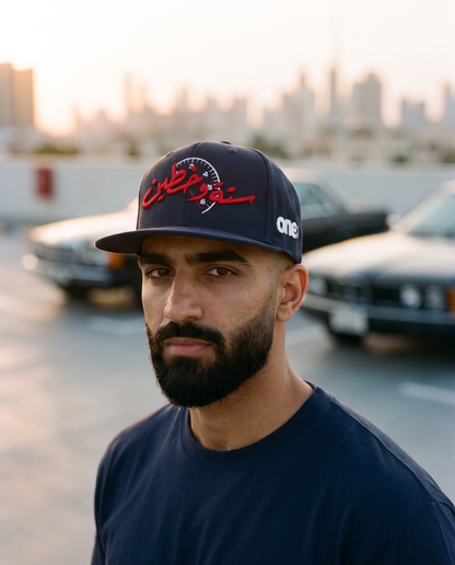 Sitta Wa Khattain navy flat brim snapback worn frontwards by male model on rooftop lot with classic cars