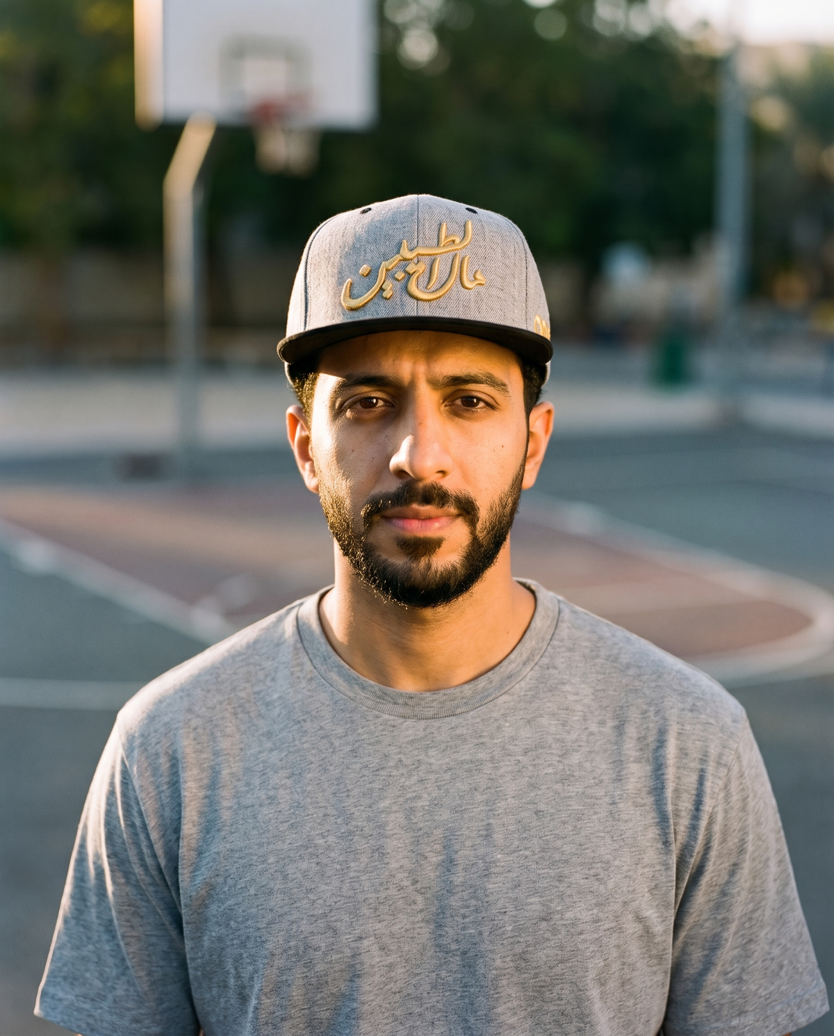 Mal Al Tayyebeen grey flat brim snapback worn frontwards by male model at a basketball court