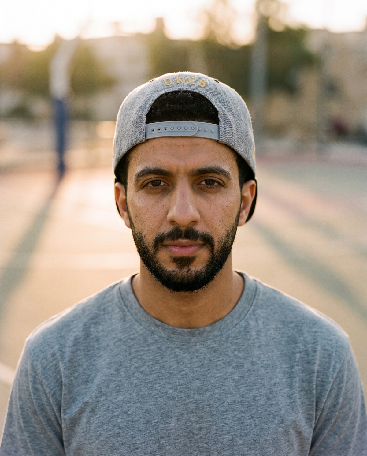 Mal Al Tayyebeen snapback worn backwards showing ONE8 back at golden hour court