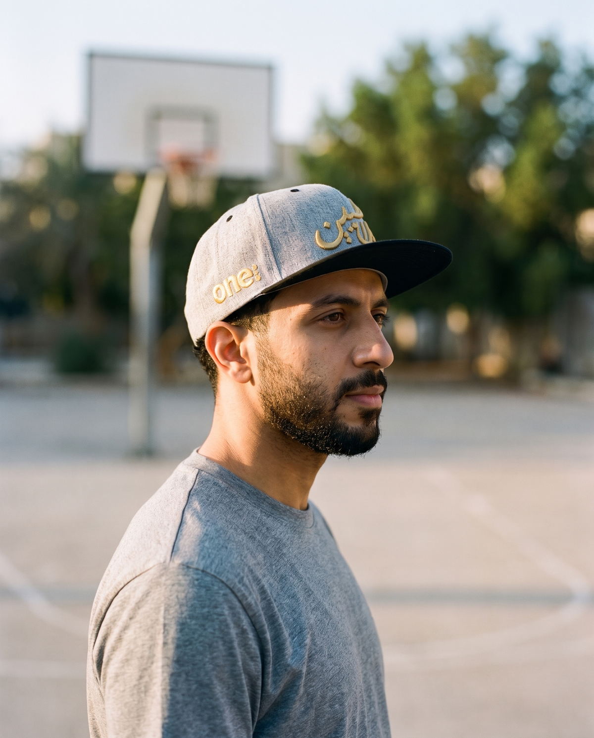 Mal Al Tayyebeen snapback side profile with gold one8 logo at basketball court