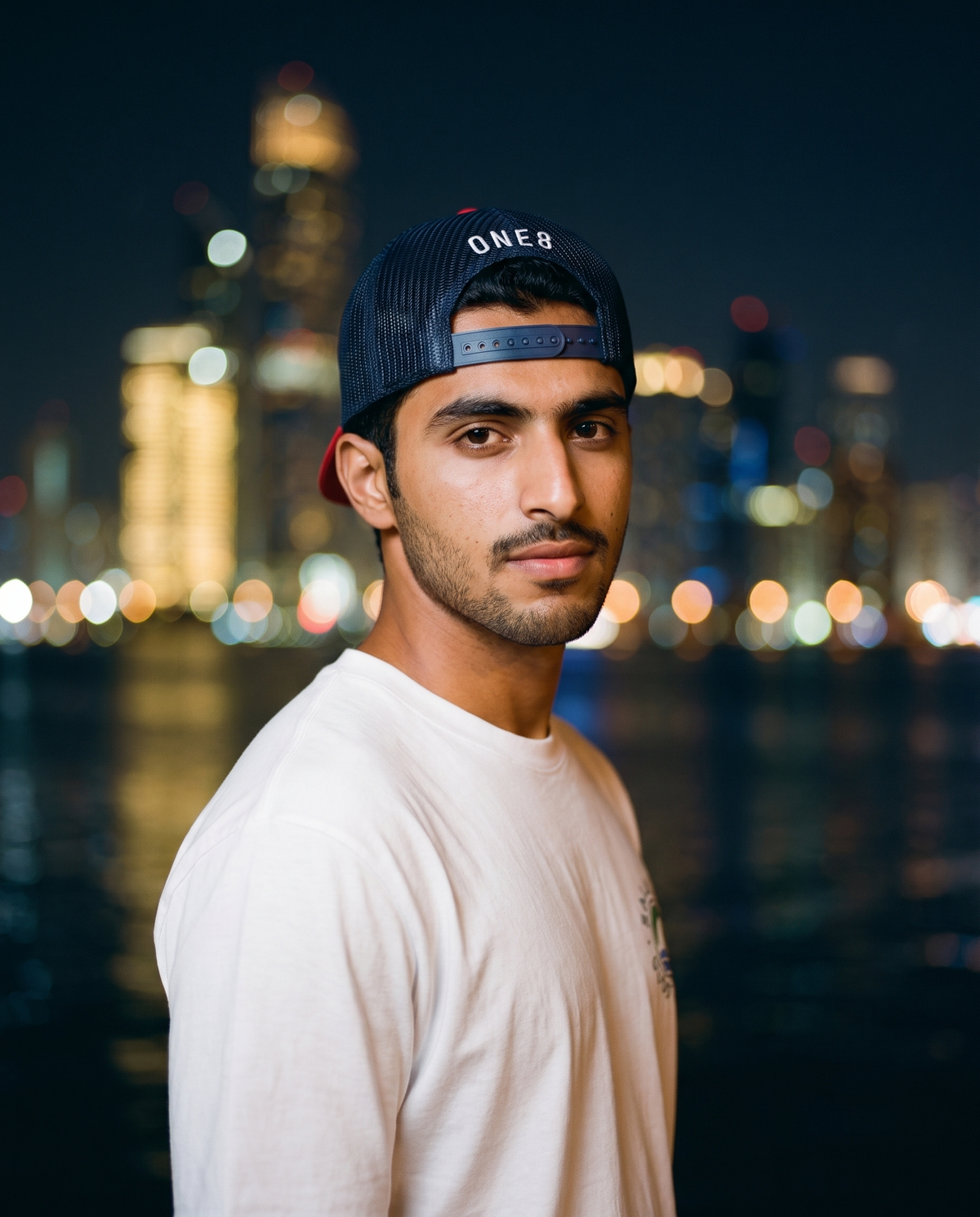 Sheikh Zayed foam trucker hat worn backwards showing navy mesh back on the corniche at night