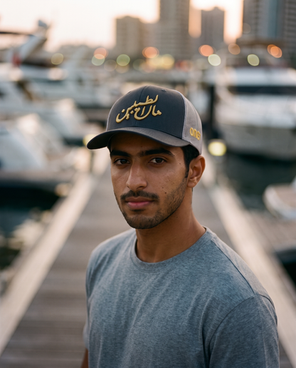 Mal Al Tayyebeen curved brim trucker worn frontwards by male model at a marina at dusk