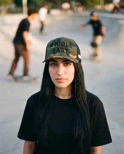 Middle East camo trucker hat worn frontwards by female model at a skate park