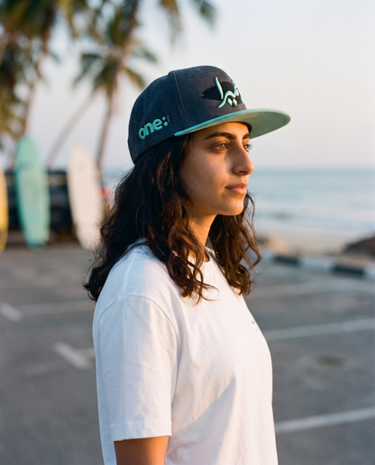 Jumeirah flat brim hat side profile with aqua brim at the beach